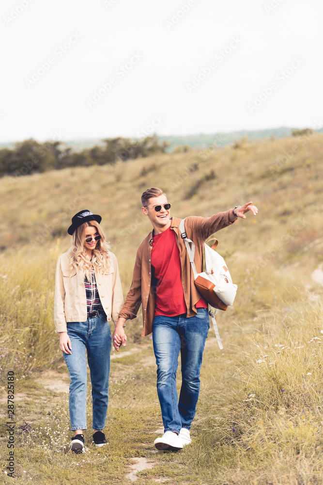 handsome man pointing with finger and walking with attractive woman handsome man pointing with finger and walking with attractive woman