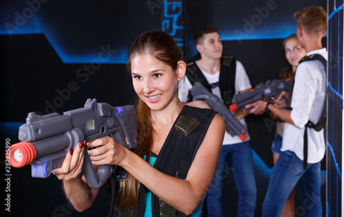 Positive girl with laser pistol during enjoying laser tag game with her friends