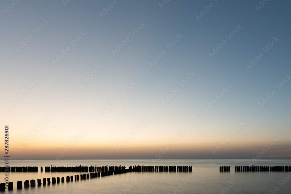 Wooden breakwater at sunset on the Baltic Sea