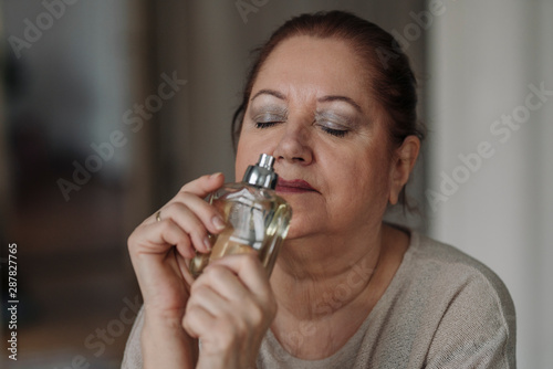 Senior woman smelling at perfume flacon