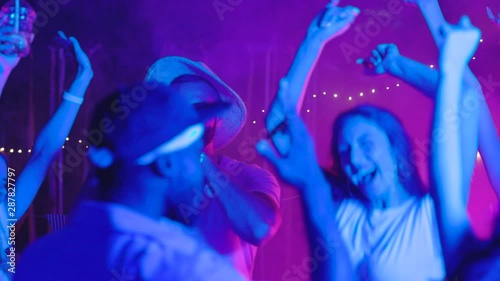 Excited young people enjoying party music dancing off celebrating summer holidays together at night.