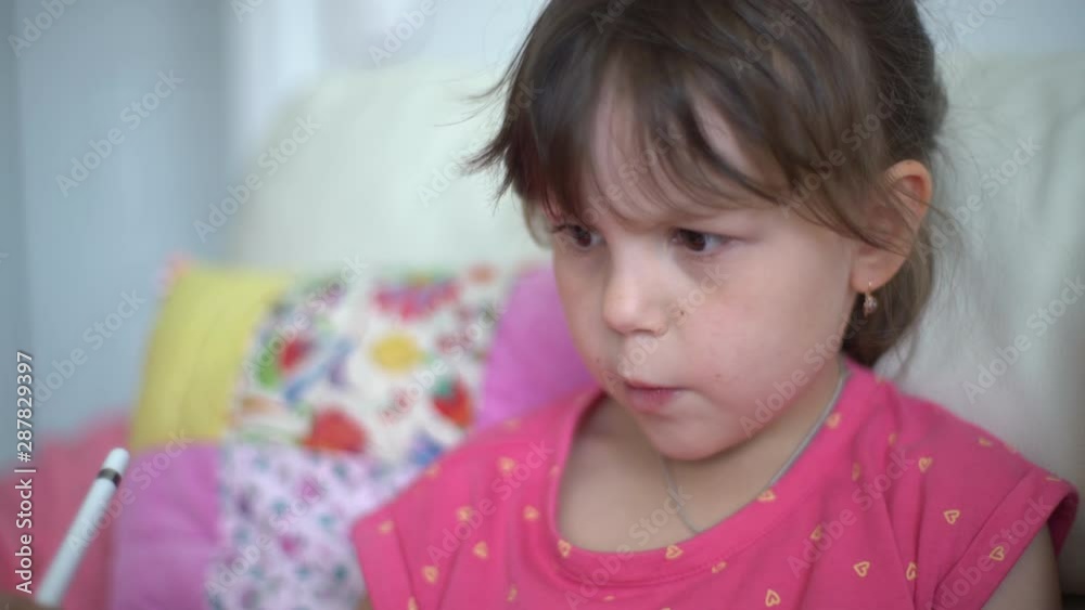 Close-up of a serious focused child draws with a digital pen on a tablet computer. Little beautiful caucasian girl uses gadget for creativity or education Close-up of a serious focused child draws with a digital pen on a tablet computer. Little beautiful caucasian girl uses gadget for creativity or education