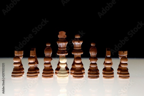 Canvas Print Black chess formation with a single white piece as a concept for undercover operations, infiltration, racial tension, ethnic minorities
