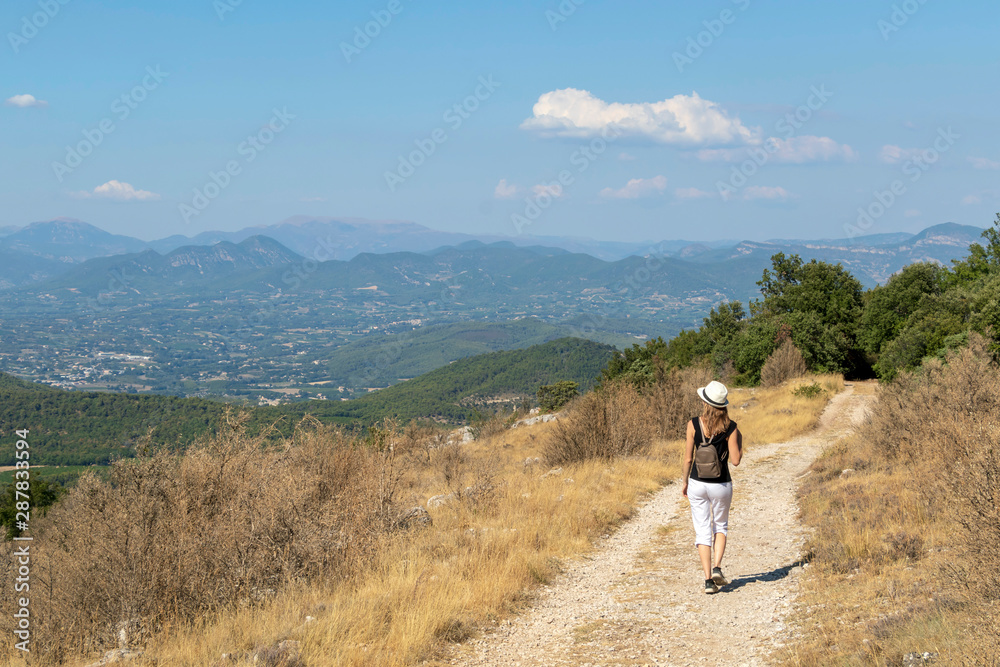 Independent solo traveler woman on the road at Dentelles de Montmirail chain of mountains in Provence in Vaucluse, France