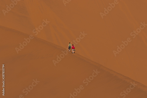Two people walking on the edge of the dune near Deadvlei Namib desert 