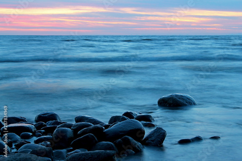 Sunset over the sea. Coastal landscape of beach with huge boulders in water at sunset, Baltic sea, Latvia.