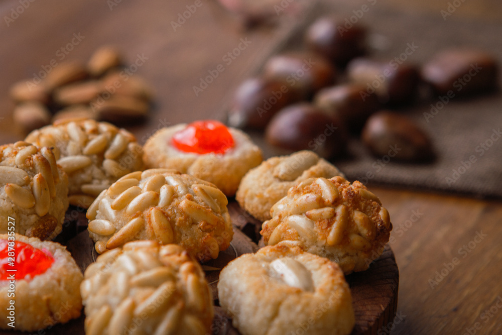 Some panellets with roasted chesnuts on the background on a wooden table. Typical snack eaten in All Saints Day in Catalonia, Spain Some panellets with roasted chesnuts on the background on a wooden table. Typical snack eaten in All Saints Day in Catalonia, Spain