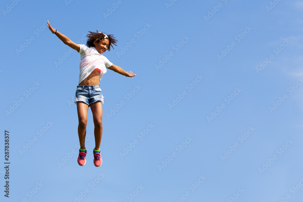 Girl in white with curly hair jump over blue sky
