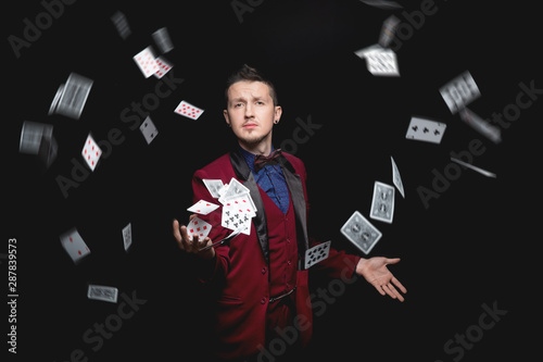 Illusionist magician man shows magic with playing cards on black background Fototapet