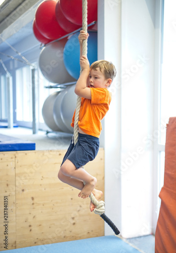 Little boy gymnast climbs a rope