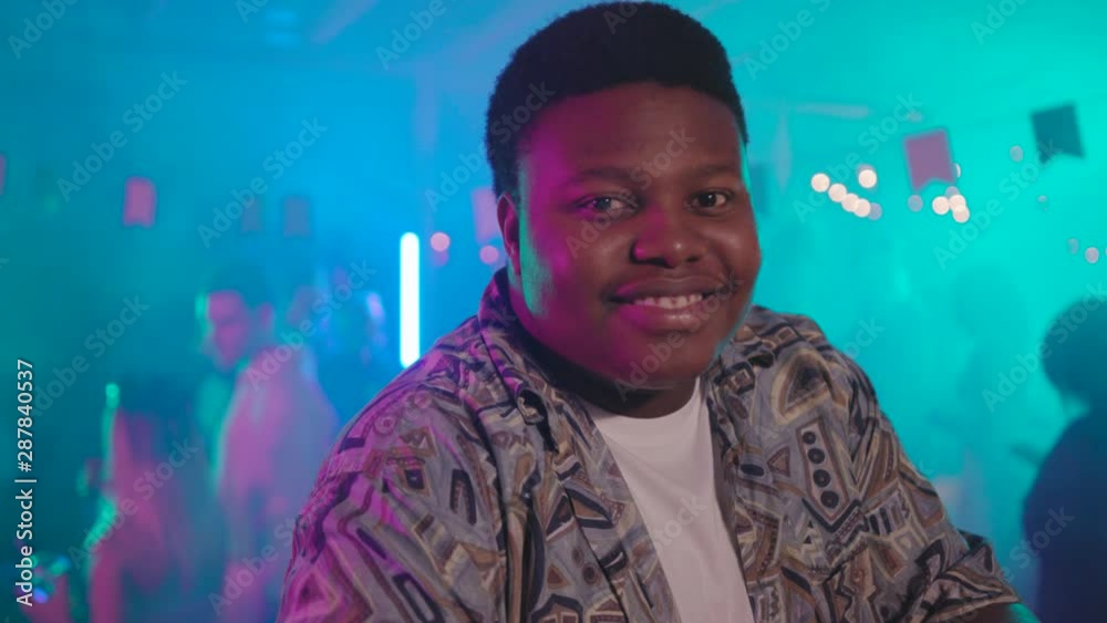 Portrait of positive joyful african boy smiling while browsing social network on smartphone at bar in the nightclub party. Portrait of positive joyful african boy smiling while browsing social network on smartphone at bar in the nightclub party.