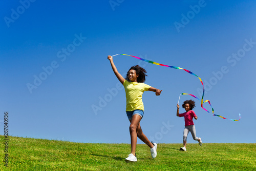 Two cool girls running fast waving with ribbons