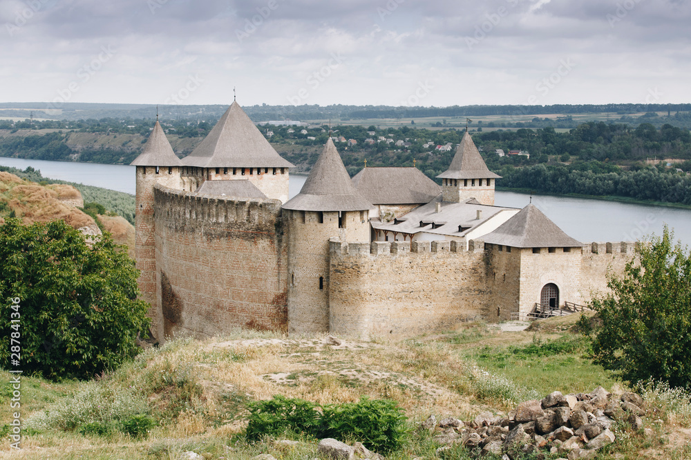 Khotyn Fortress complex, Ukraine. A medieval Romanesque castle protected by a stone fortress and a river on one side. Stone beautiful castle on the mountain Khotyn Fortress complex, Ukraine. A medieval Romanesque castle protected by a stone fortress and a river on one side. Stone beautiful castle on the mountain