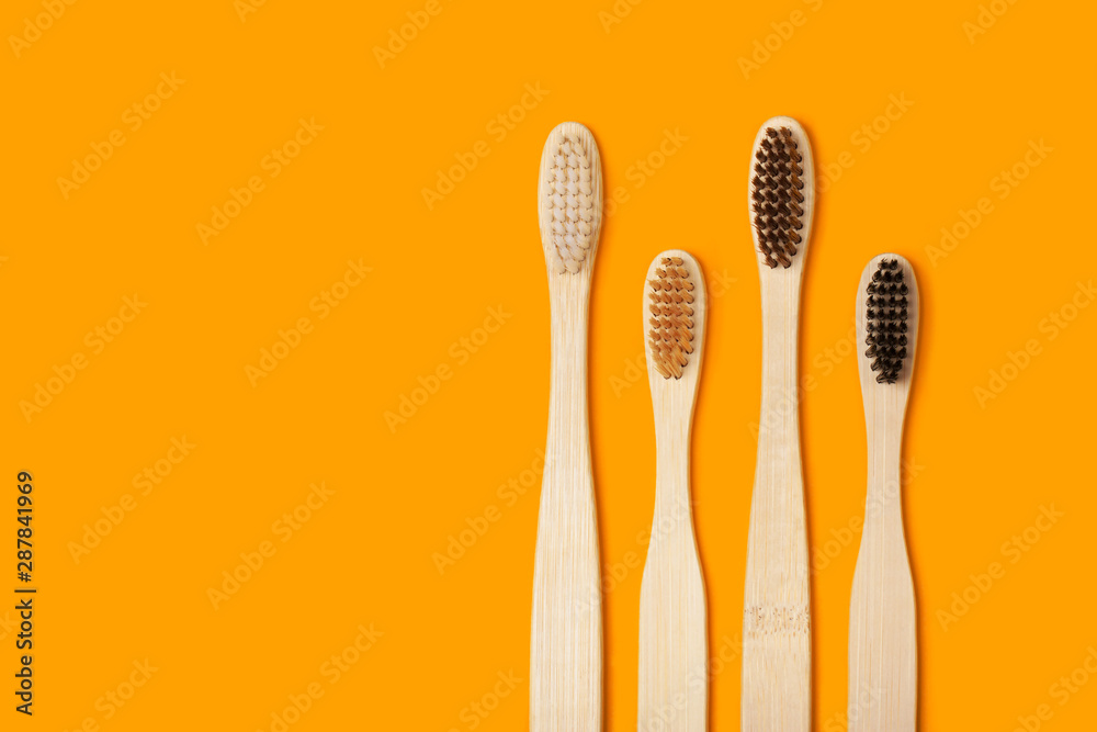 Four eco-friendly bamboo toothbrushes on a juicy orange background.. Copy space. Zero waste concept, plastic-free, organic, eco-friendly shopping Four eco-friendly bamboo toothbrushes on a juicy orange background.. Copy space. Zero waste concept, plastic-free, organic, eco-friendly shopping