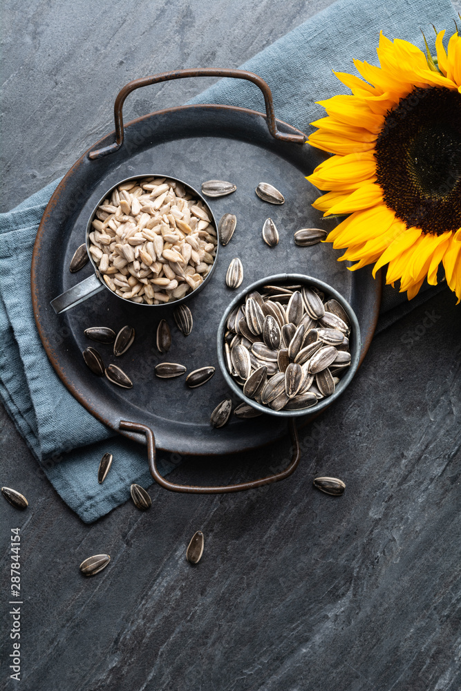 Healthy snack, a heap of whole and peeled sunflower seeds in jars