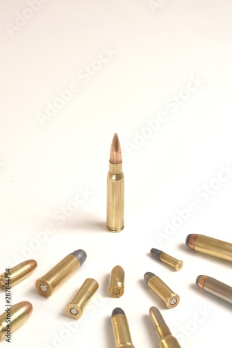 A single bullet standing in front of several smaller bullets of various calibers.