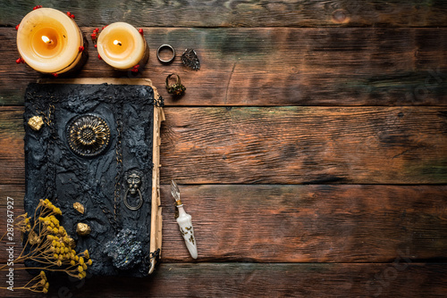 Magic book and magical potion in a vial on a brown wooden table background with copy space. photo