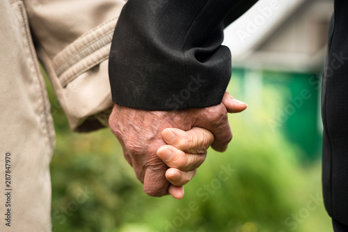 Elderly people holding hands close up.