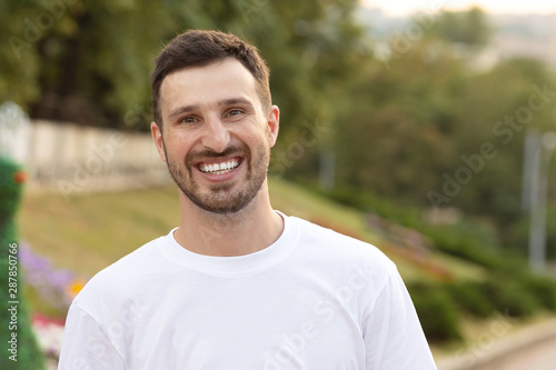 Close up portrait of handsome man with beard smiling outside.