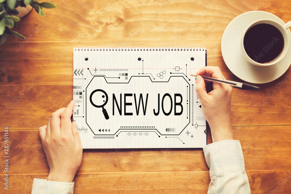Searching new job theme with a person writing in a notebook on a wooden table Searching new job theme with a person writing in a notebook on a wooden table