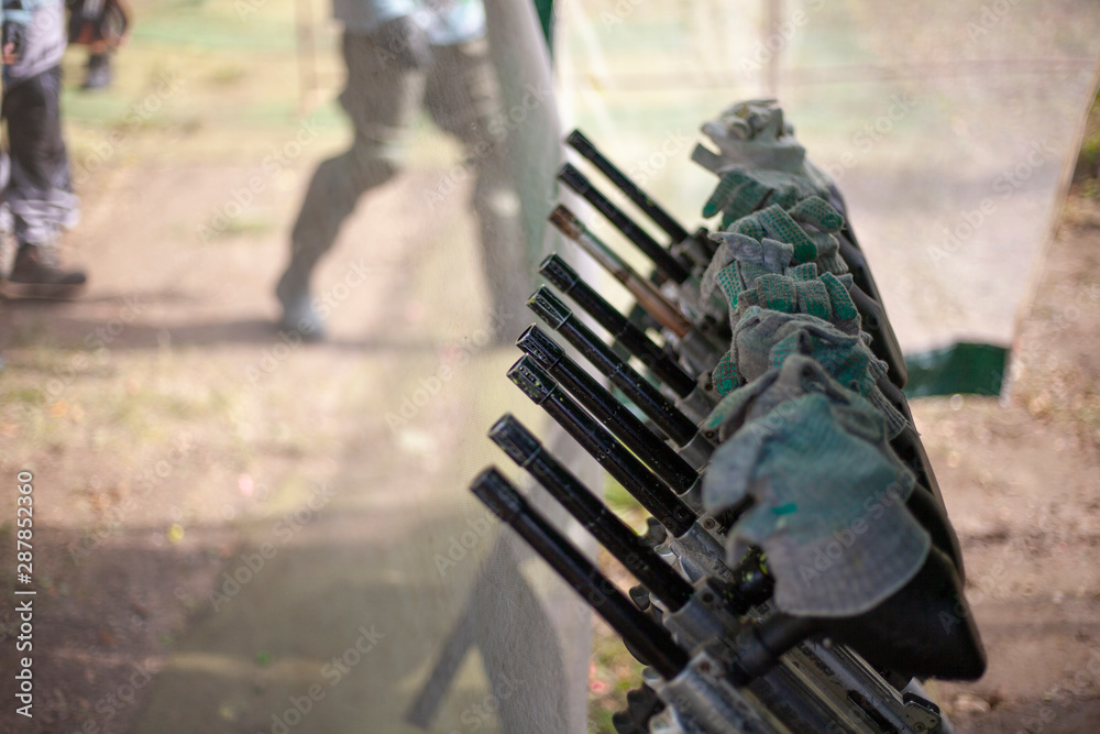 Fototapeta premium Paintball markers. Shotguns stand in a row. Stock for strategic battle. A lot of weapons are on the rack.