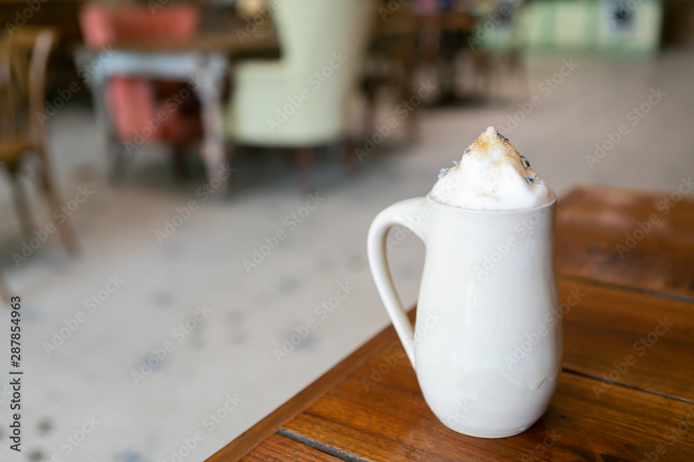 Lavender london fog tea latte with steamed milk and sugar on table in cafe, cafe in background, copy space