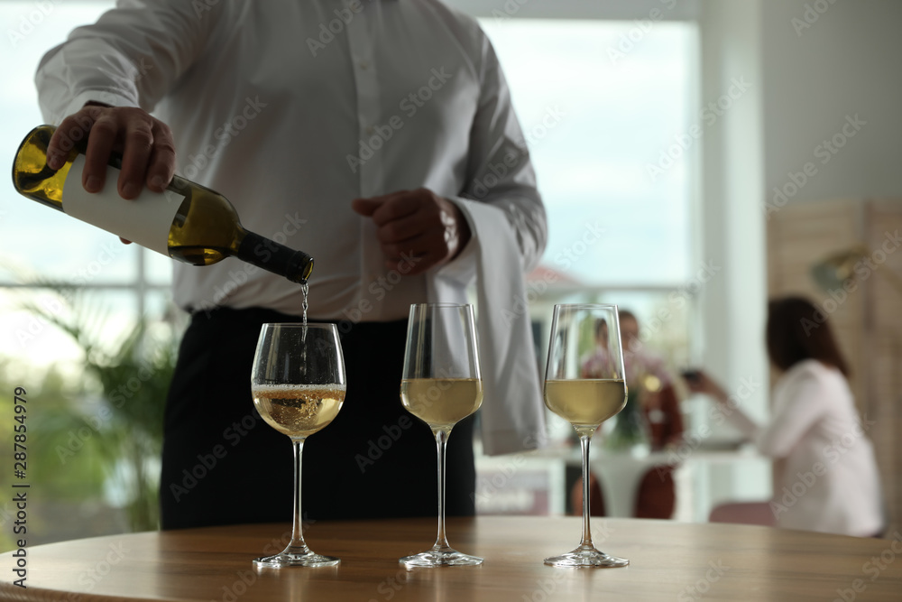Waiter pouring wine into glass in restaurant, closeup Waiter pouring wine into glass in restaurant, closeup