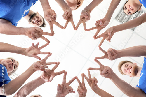 Team of volunteers putting their hands together on light background, bottom view