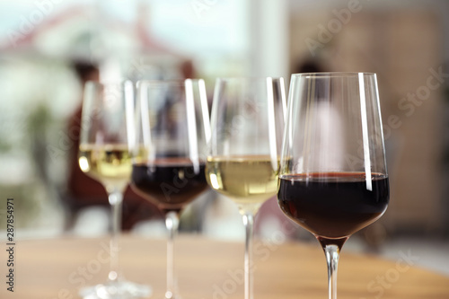 Glasses with different wines on table against blurred background