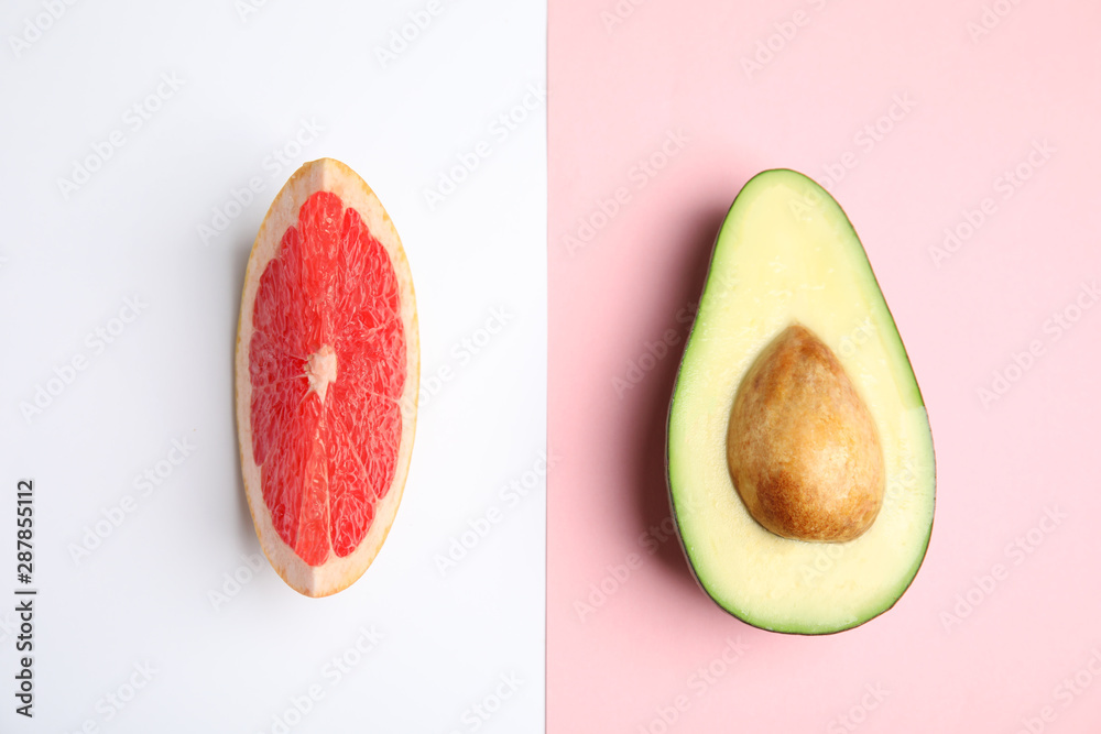 Cut ripe avocado and grapefruit on color background, flat lay