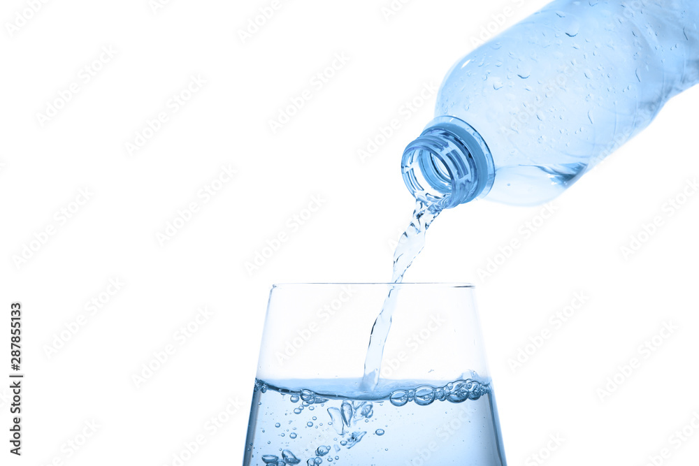 Pouring water from bottle into glass against blue background. Refreshing drink Pouring water from bottle into glass against blue background. Refreshing drink