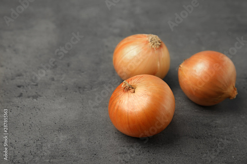 Ripe onions on grey table  space for text