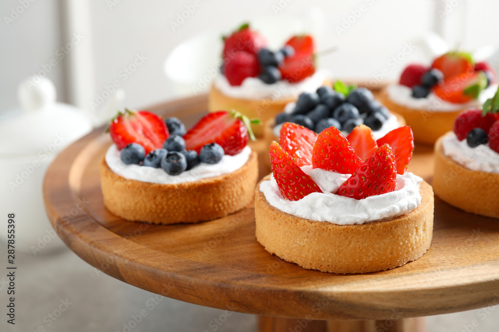 Cake stand with different berry tarts on table. Delicious pastries - obrazy, fototapety, plakaty 