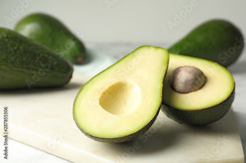 Delicious ripe avocados on table against light background