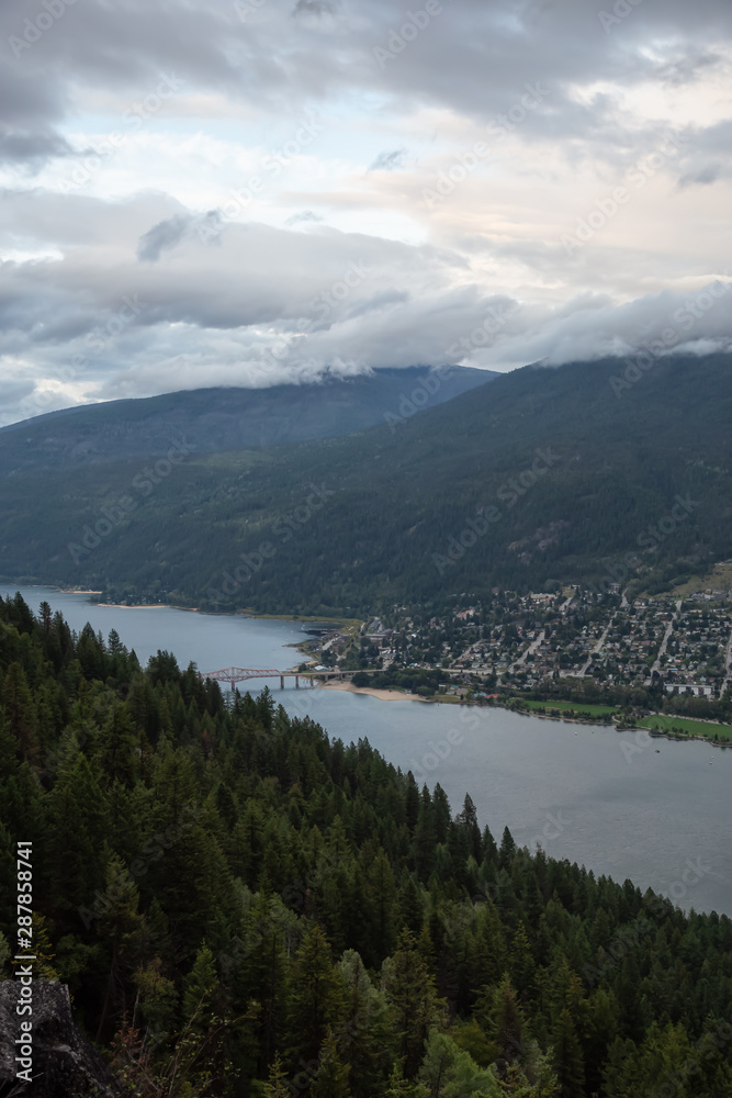 Beautiful View of a small Town, Nelson, during a dark and cloudy sunset. Located in the Interior of British Columbia, Canada.