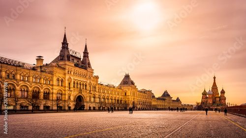 Tourists visiting St. Basils Cathedral and GUM shopping mall on Red Square in Moscow at sunrise, Russia