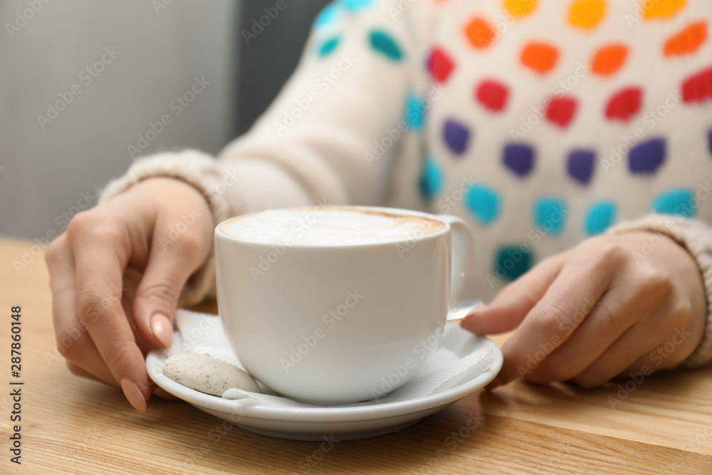 Woman with cup of aromatic cacao at table, closeup