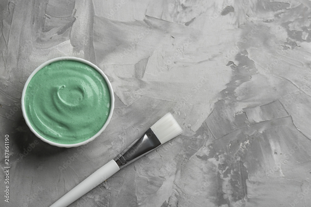 Spirulina facial mask and brush on grey table, flat lay. Space for text
