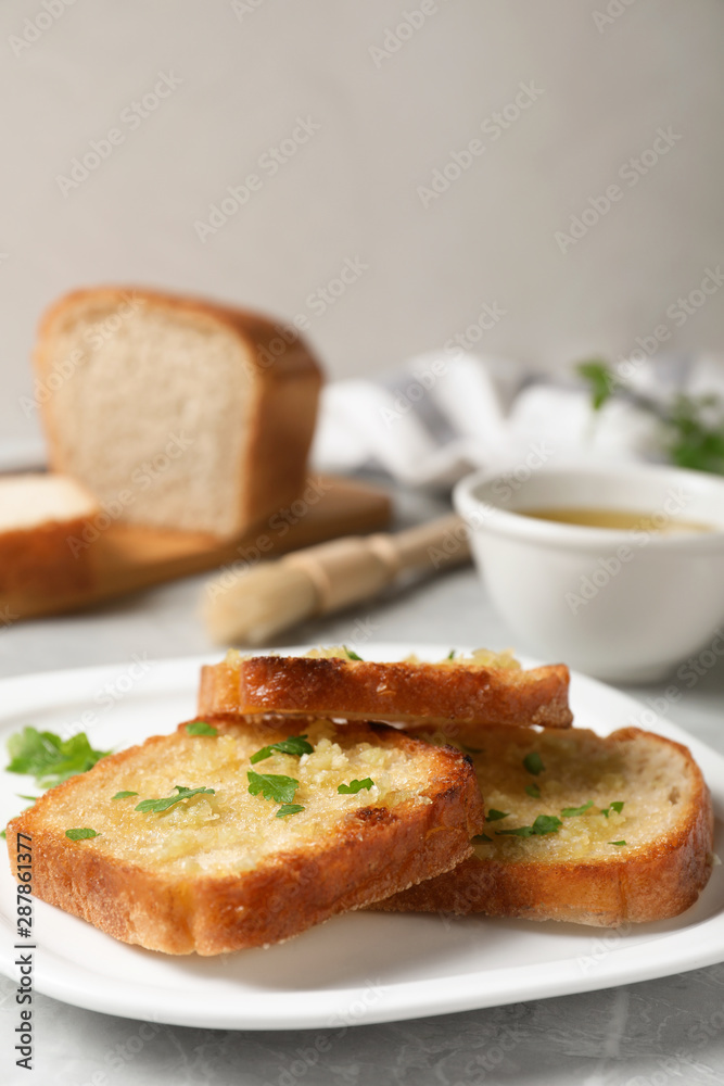 Slices of toasted bread with garlic and herb on light grey marble table