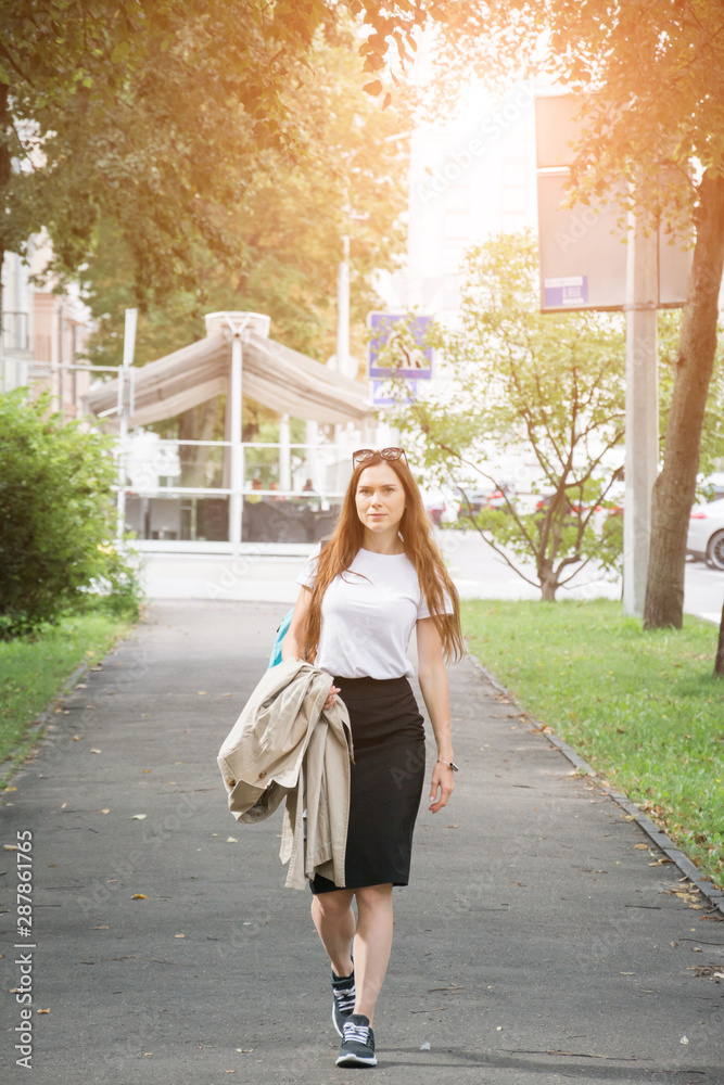 Summer sunny lifestyle fashion portrait of young stylish hipster woman walking on the street