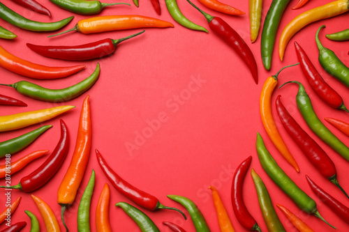 Frame made with different chili peppers on red background, flat lay. Space for text