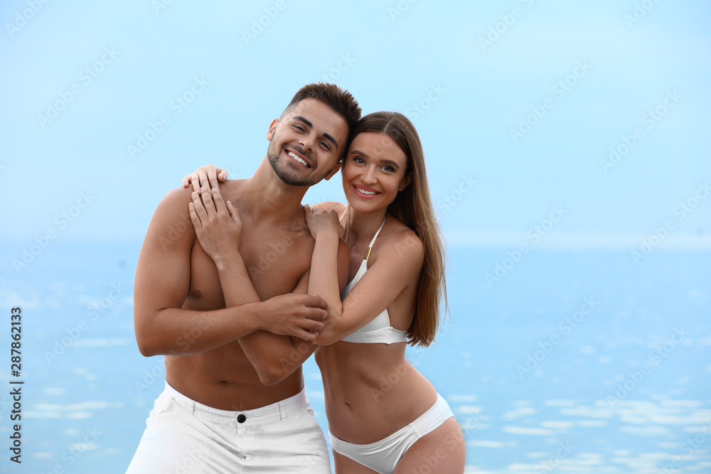 Young woman in bikini with her boyfriend on beach, space for text. Lovely couple Young woman in bikini with her boyfriend on beach, space for text. Lovely couple