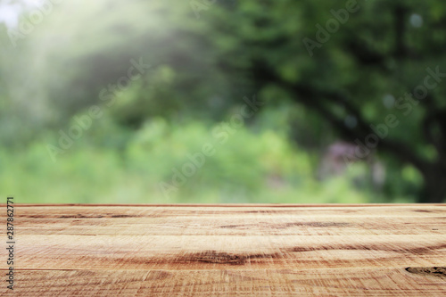 Blurred abstract green bokeh of garden and wooden table background.