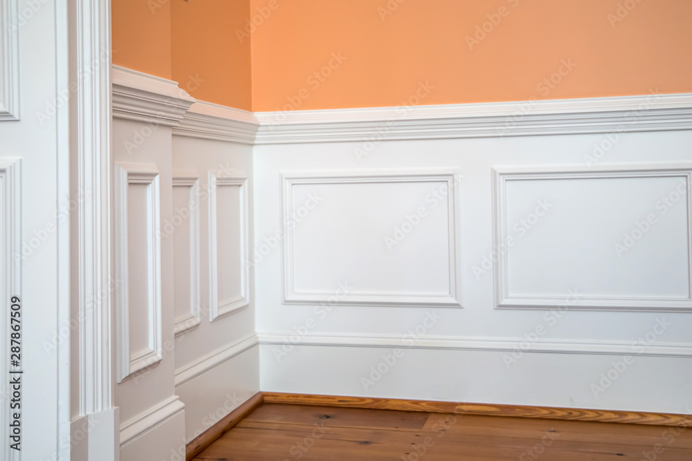 Fototapeta premium white wainscoting and chair rail on wall of orange peach dining living room of home house