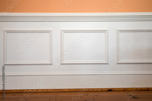 white wainscoting and chair rail on wall of orange peach dining living room of home house photo