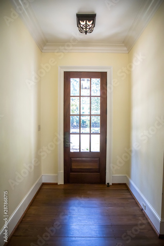 long hallway with hardwood floors and a stained wood door leading outside