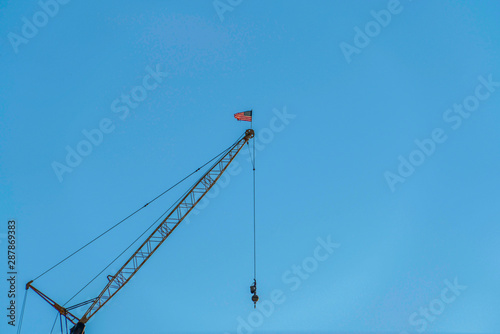 Metal construction crane viewed from below against cloudless blue sky