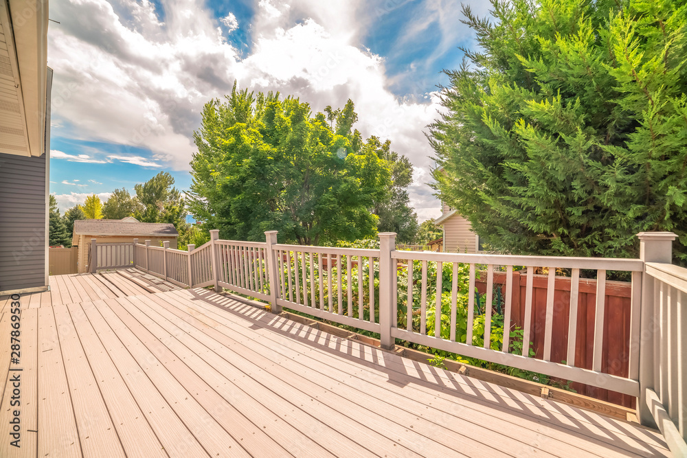 Spacious balcony of home with view of trees and cloudy blue sky on a sunny day Spacious balcony of home with view of trees and cloudy blue sky on a sunny day