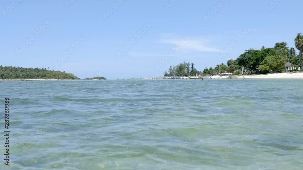 Low angle view over shallow water just offshore from Samui Island, Thailand. Beautiful green coast, turquoise water and blue sky of this tropical paradise Low angle view over shallow water just offshore from Samui Island, Thailand. Beautiful green coast, turquoise water and blue sky of this tropical paradise