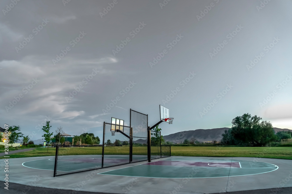 Half basketball courts with view of majestic mountain and overcast gray sky  Stock Photo